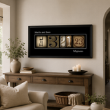 a living room with a wooden console table, a sofa, and a potted plant. Above the console table, there is a framed collage of numbers and letters that spell out "Est. 3.1.23 Mignano".