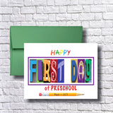 A colorful greeting card with the text "HAPPY FIRST DAY of PRESCHOOL" and a pencil, placed on a white brick wall.