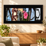 Nature letter art with six original tree and pink hibiscus photographic panels in a black panoramic frame above a wood console