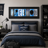 A bedroom with a large framed word art piece that spells out "HOCKEY" on the wall above a bed with blue and gray bedding. The room also has a nightstand, a lamp, and a trophy on display.