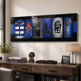 a large black and white framed artwork with various police-related items such as a gun, boots, a helmet, and a badge, displayed on a wall above a wooden desk with a lamp, books, and a plant.