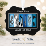 A black ornament with musical notes and symbols, placed on a white surface with pine branches in the background.