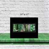 A framed artwork displaying the name "ALEXANDER" in a creative and artistic manner, with the letters arranged in a unique design.